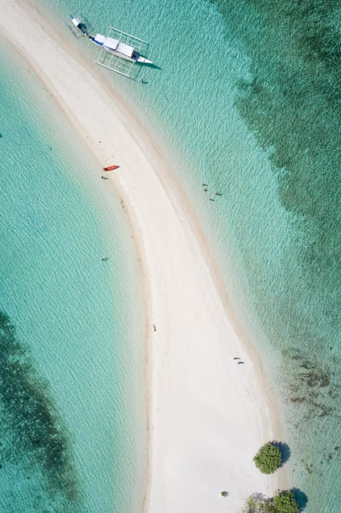 Aerial view of white sandbar with turquoise tropical water and boat