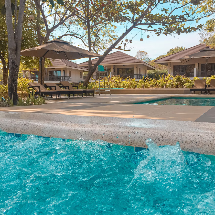 Beach resort pool and villas near tropical coast